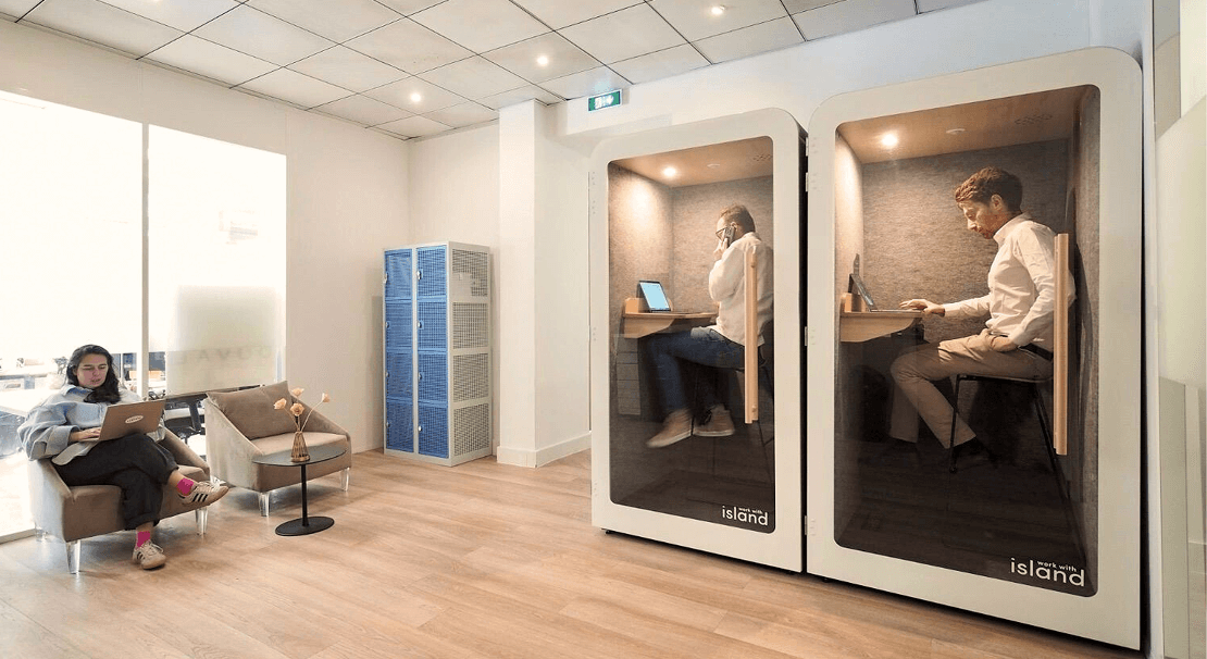 Espace de coworking moderne avec cabines insonorisées pour appels et travail au calme, et coin détente avec fauteuils confortables