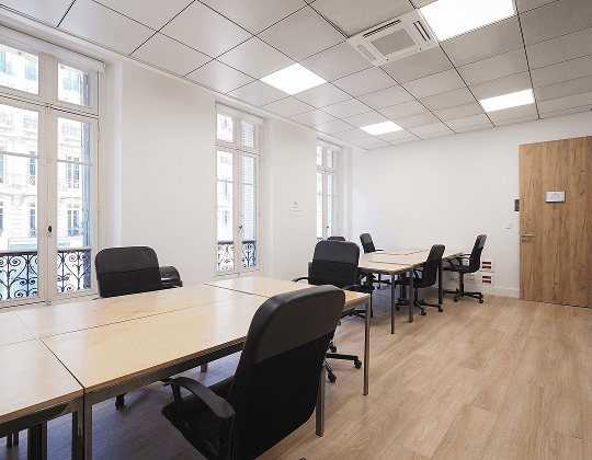 Bureau flexible et lumineux avec grandes fenêtres, mobilier moderne et espaces de travail partagés