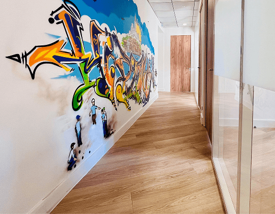 Couloir moderne avec parquet clair et fresque graffiti colorée sur le mur, ambiance dynamique et créative
