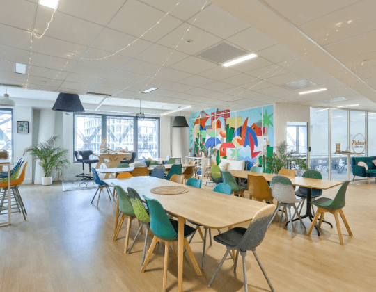 Espace commun convivial à Rennes EuroRennes avec des tables en bois, des chaises colorées, une décoration murale artistique et une ambiance lumineuse