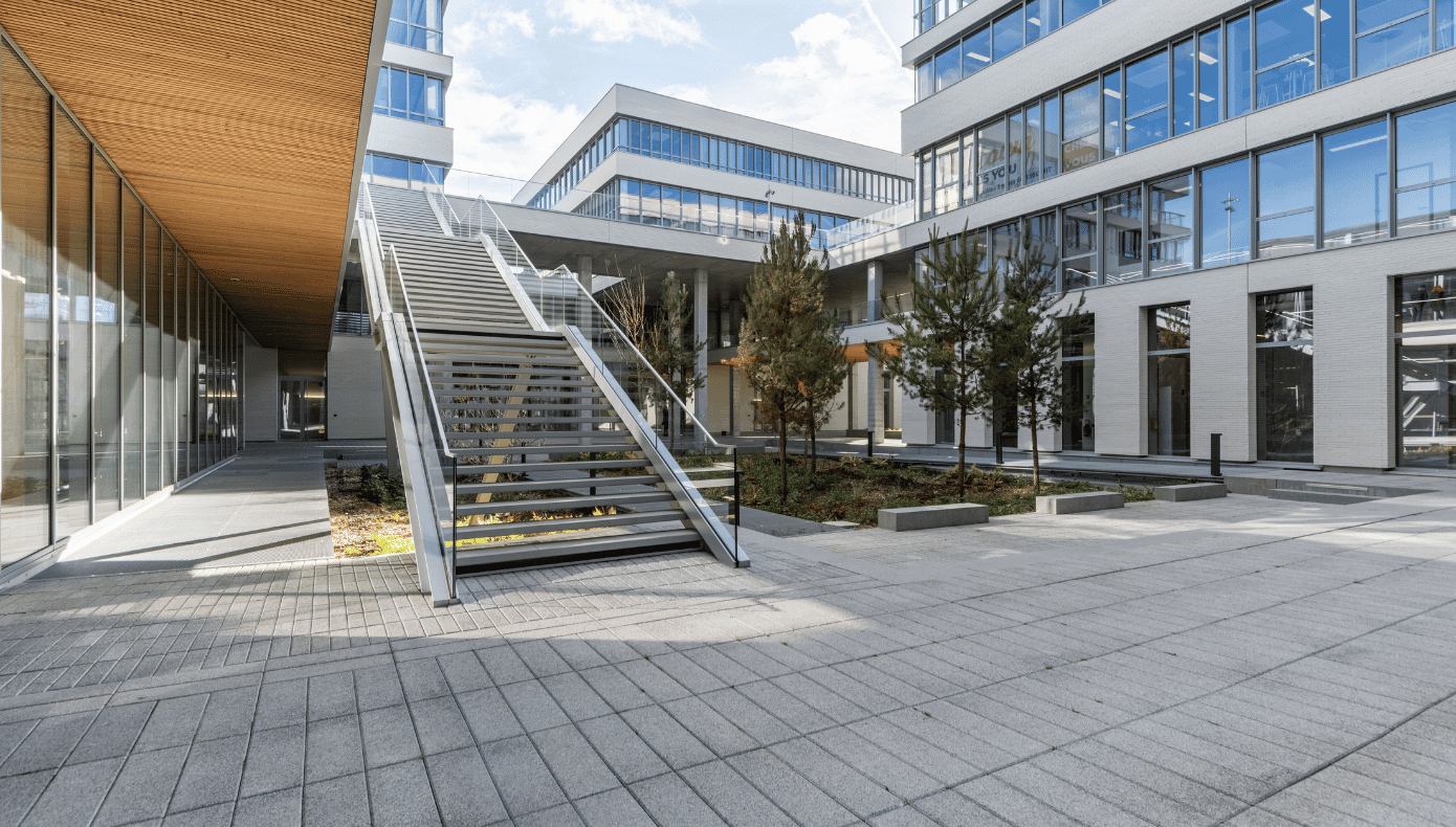 Cour intérieure de Lille Euratech Cour intérieure de Hiptown Lille Euratech entourée de bâtiments vitrés, avec escalier extérieur et espace paysager.