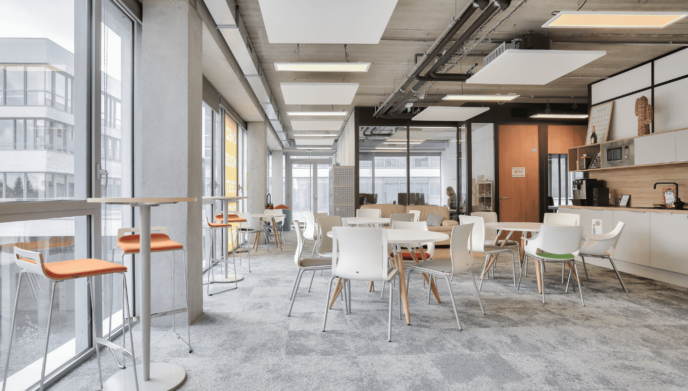 Espace commun et cuisine à Lille Euratech Espace commun de coworking à Hiptown Lille Euratech, avec tables, chaises, comptoirs et cuisine partagée.