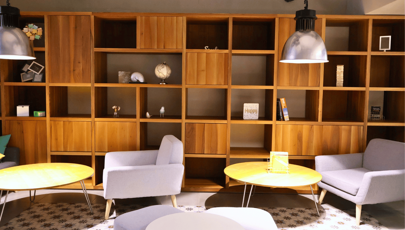 Espace détente Hiptown à Sèvres avec fauteuils, tables basses, grande bibliothèque en bois et luminaires suspendus.