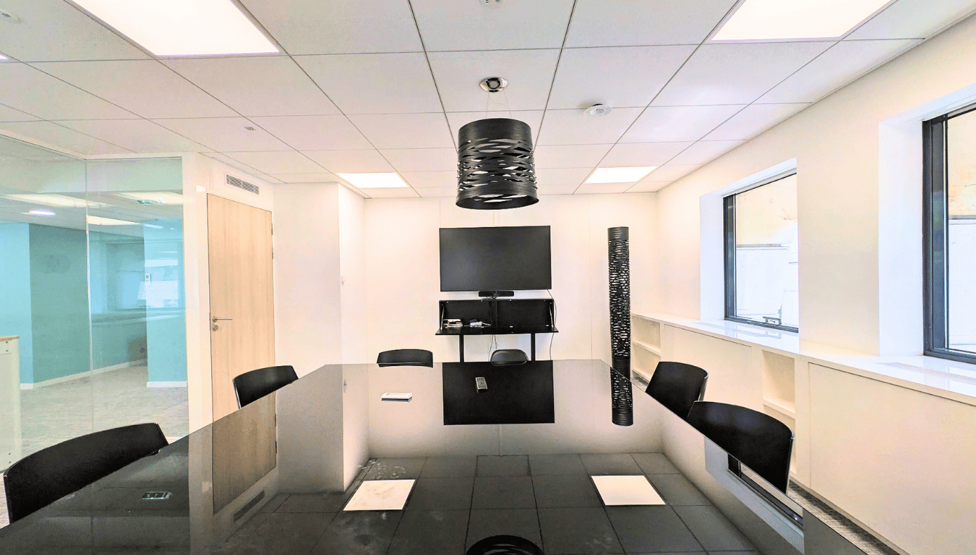 Salle de réunion Hiptown à Sèvres avec grande table noire, plusieurs sièges, écran mural et cloisons vitrées.