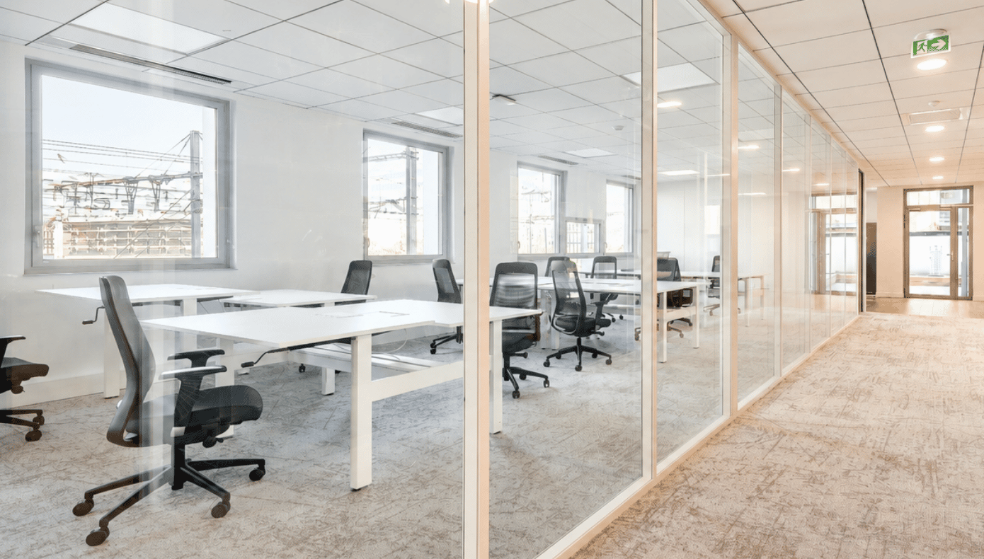 Bureau fermé vitré à Part-Dieu Equinox avec plusieurs postes de travail, chaises de bureau et fenêtres.
