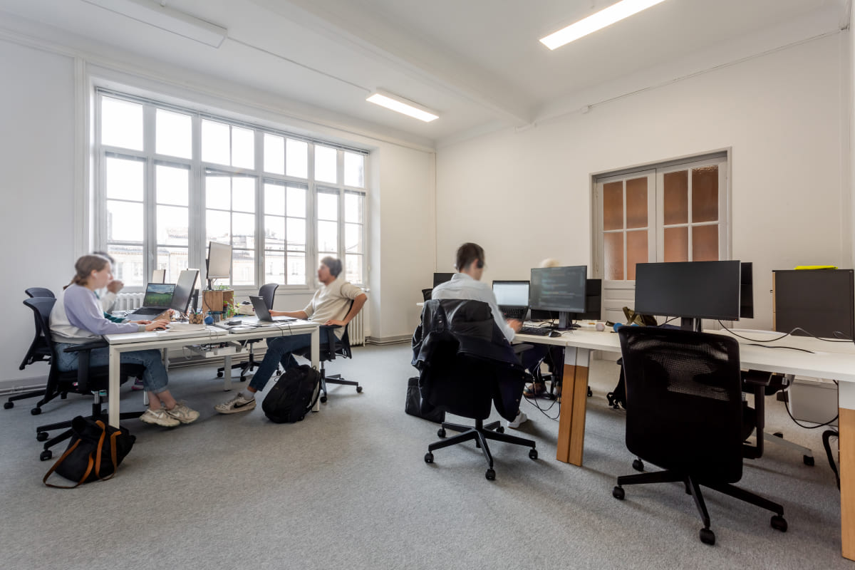 Bureaux privatifs lumineux chez Hiptown Place de la Bourse, à Bordeaux, avec grandes fenêtres et postes de travail équipés