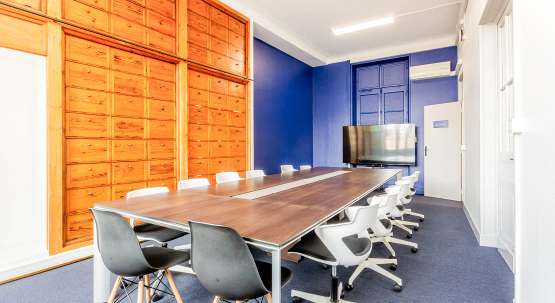 Salle de réunion élégante chez Hiptown Place de la Bourse à Bordeaux, avec mur en bois, grande table et écran de présentation