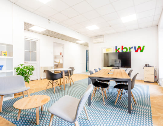 Espace de travail moderne chez Hiptown Place de la Bourse à Bordeaux avec écran de présentation, mobilier design et ambiance lumineuse