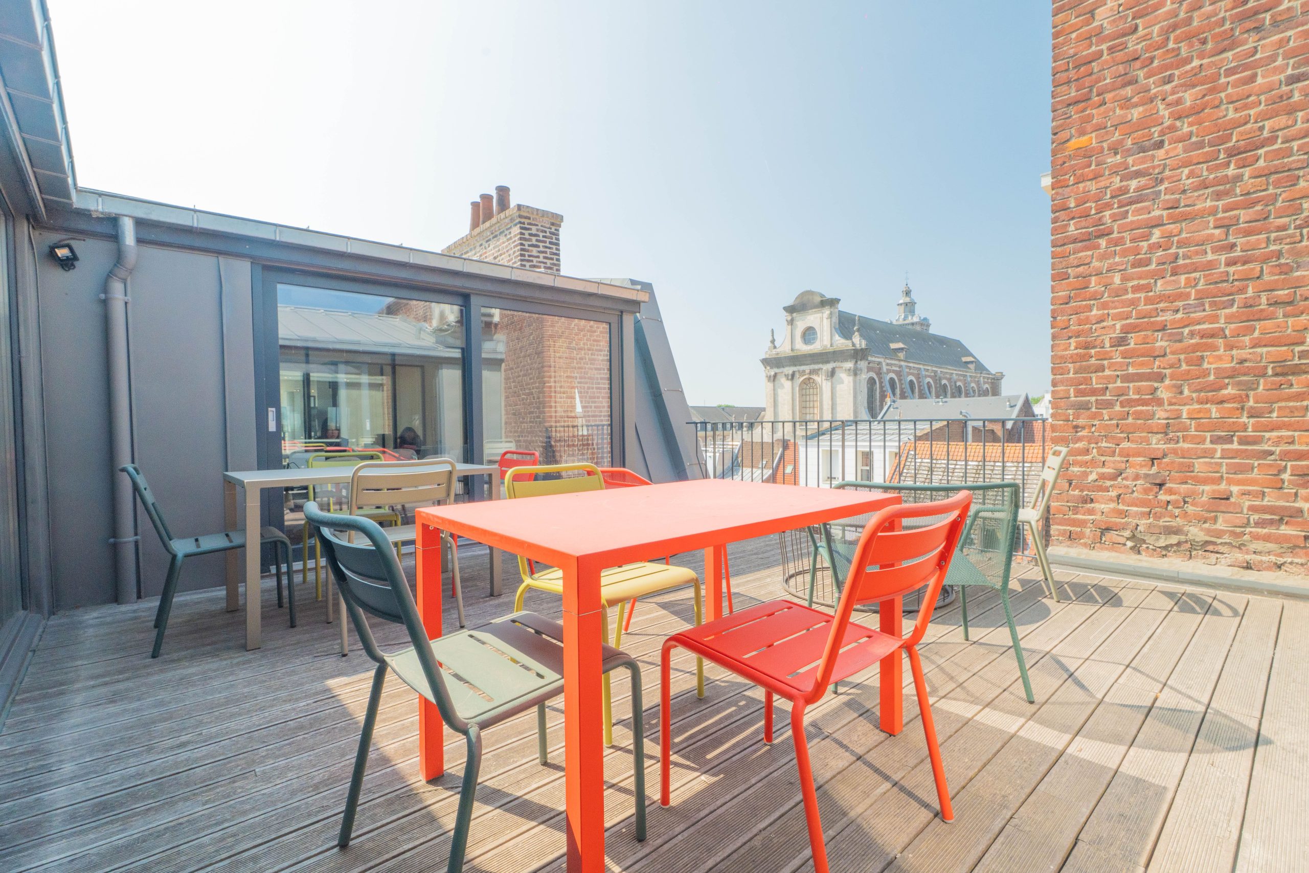 Terrasse aménagée avec vue sur les toits de Lille et l’église Saint-Étienne, espace détente extérieur dans les bureaux opérés Hiptown Grand Place – location de bureaux flexibles à Lille centre.