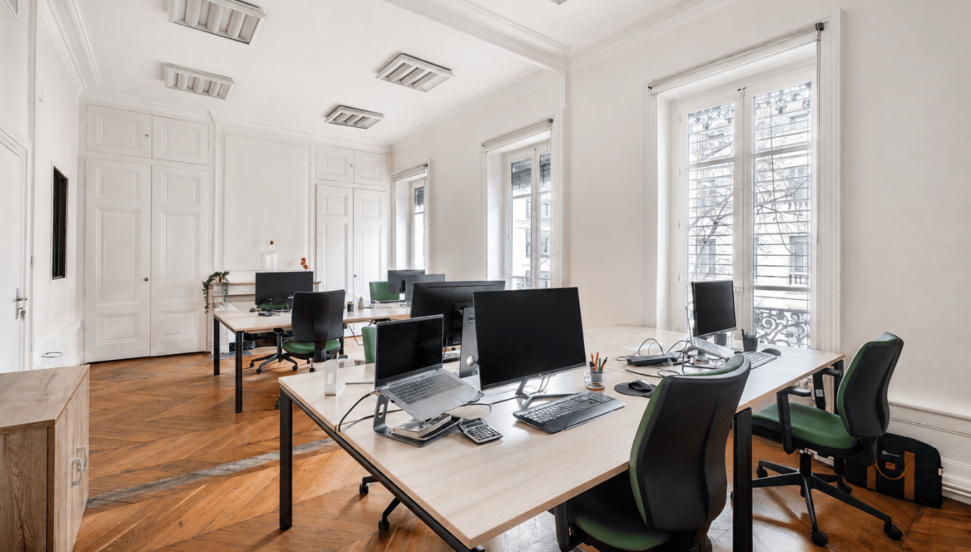 Bureau fermé Hiptown à Lyon avec plusieurs postes de travail équipés, de grandes fenêtres et un parquet en bois