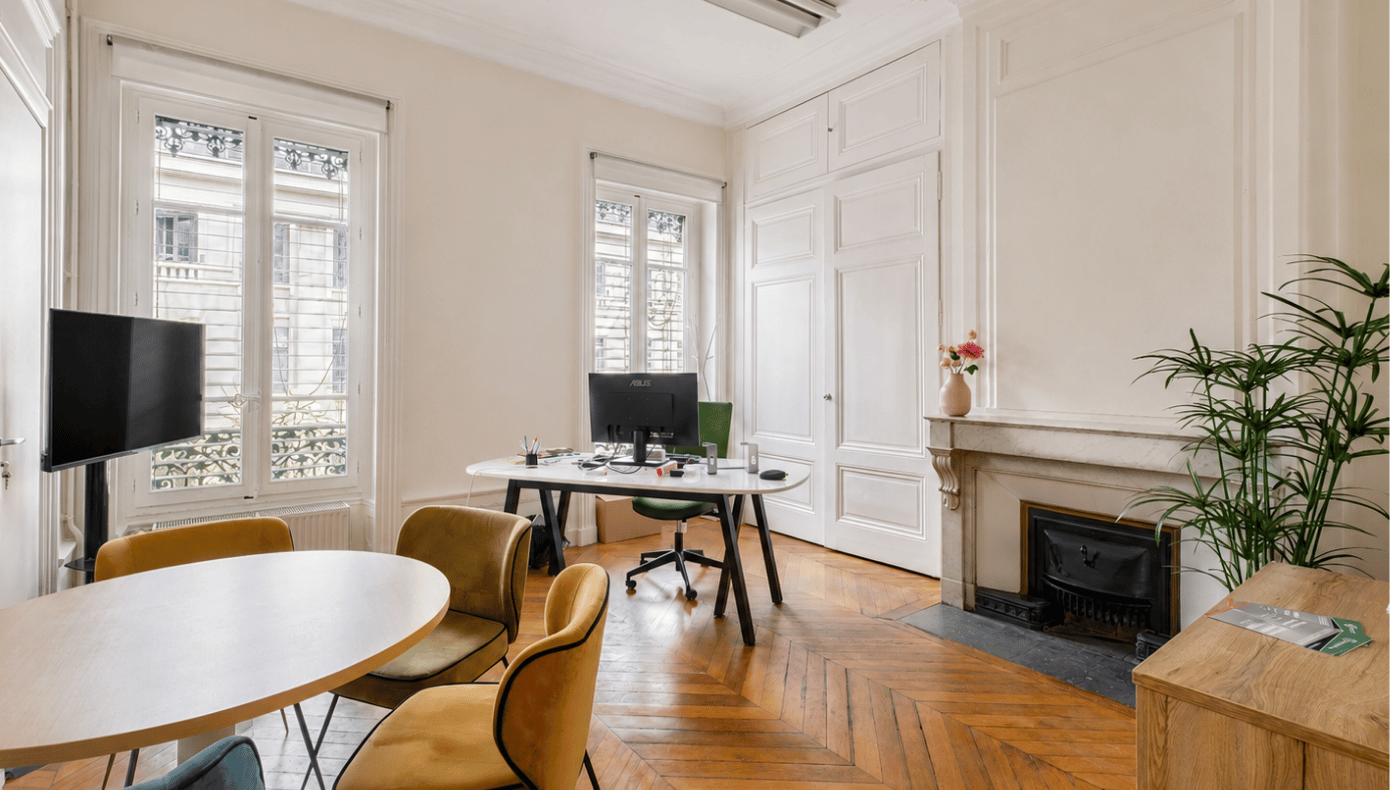 Salle de réunion Hiptown à Lyon avec table ronde, chaises, poste de travail, cheminée et grandes fenêtres
