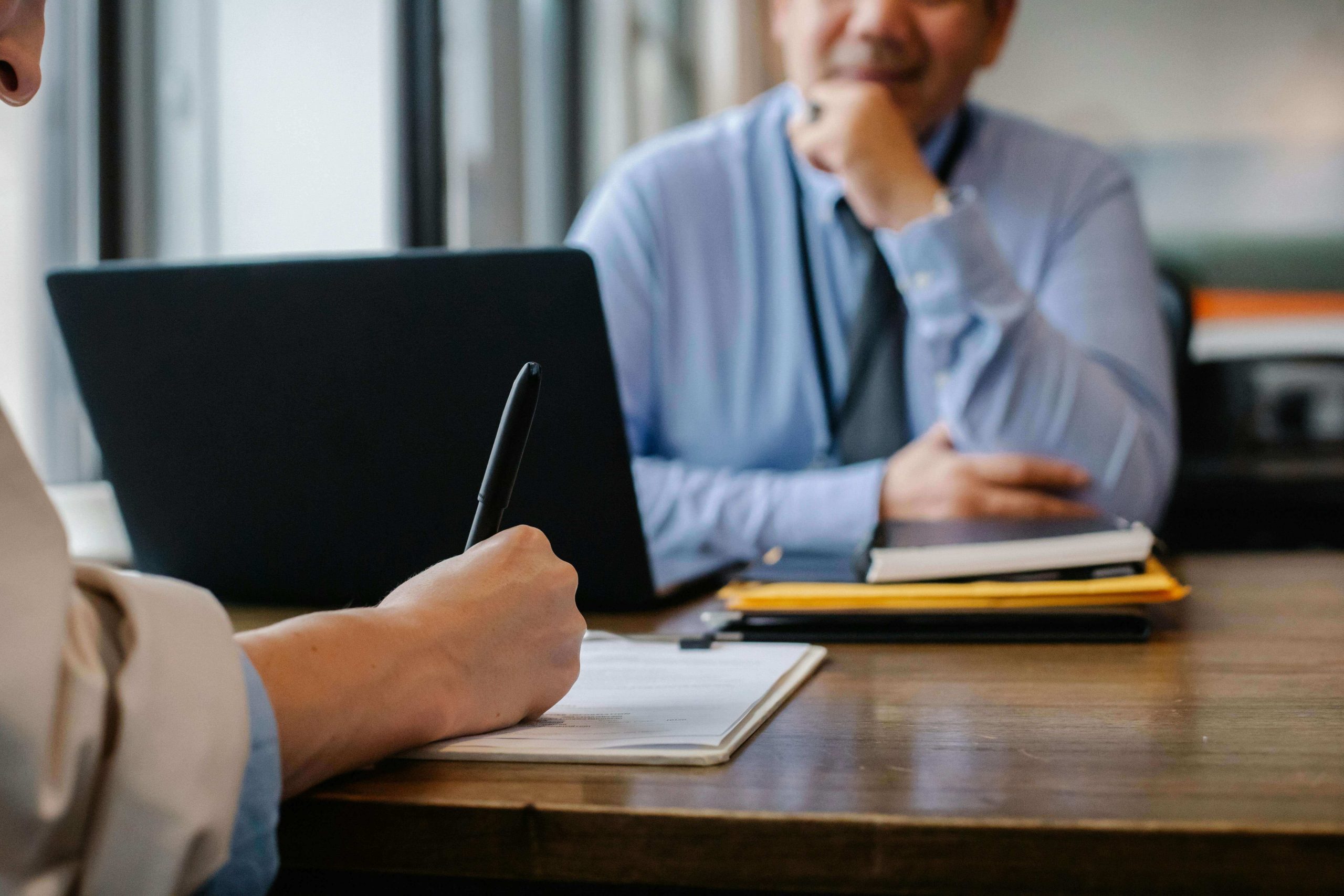 Un recruteur qui écrit des notes sur le candidat qui lui fait face lors d'un entretien