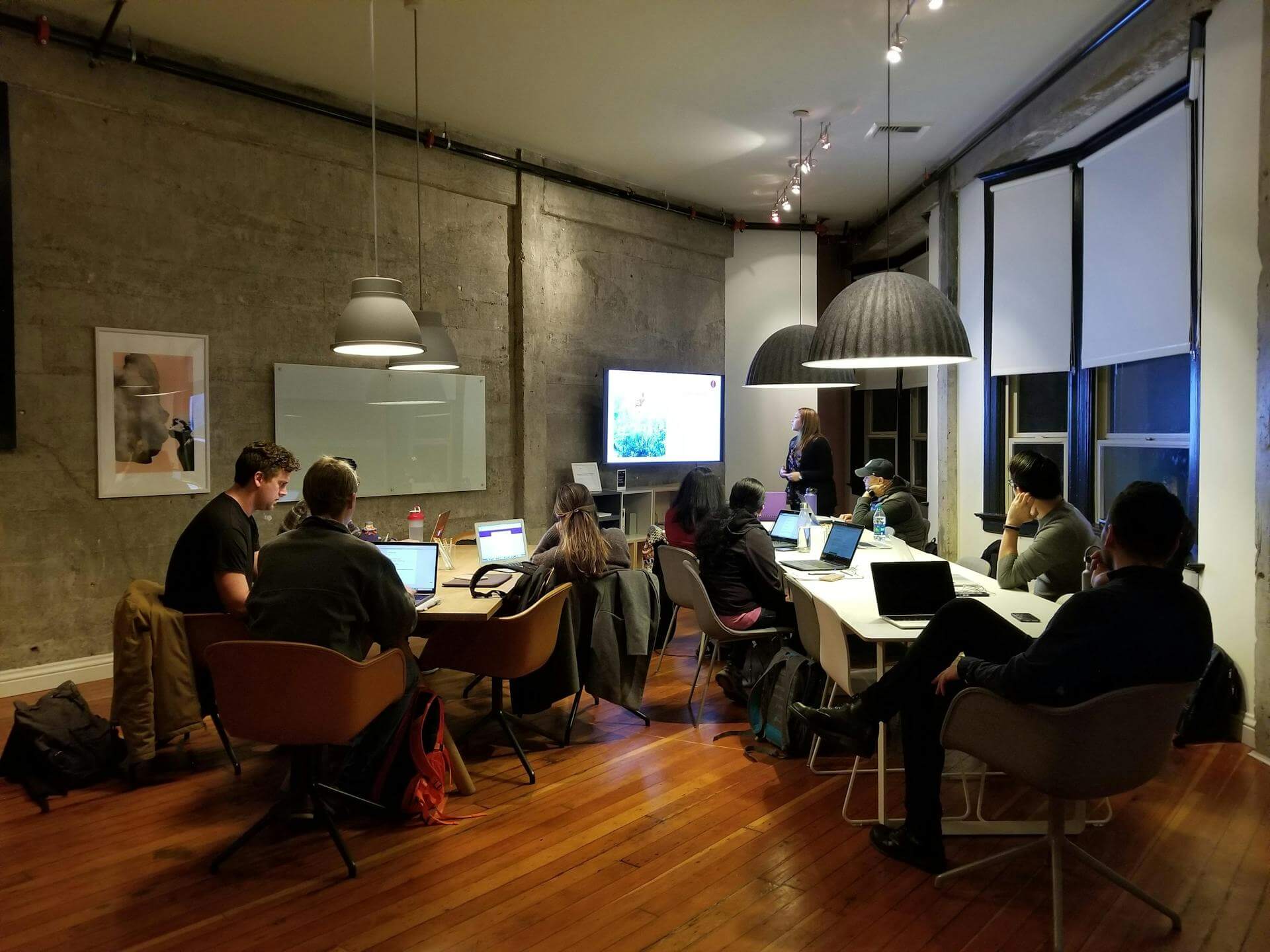 Réunion collaborative dans un espace de coworking, avec plusieurs personnes travaillant sur ordinateurs et une présentation