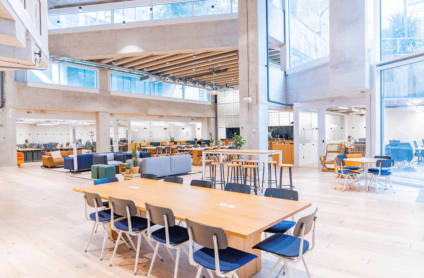 Grand espace de coworking moderne avec mezzanine, mobilier en bois, larges baies vitrées et ambiance lumineuse