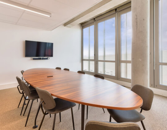 Salle de réunion Hiptown : table ovale spacieuse, chaises confortables, écran TV et baie vitrée lumineuse