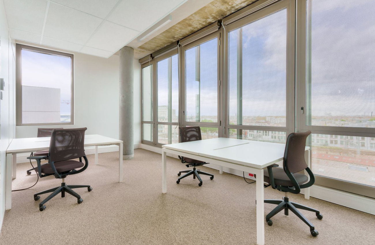 Bureau lumineux avec grandes fenêtres, tables blanches et chaises ergonomiques au Quai de Paludate à Bordeaux.