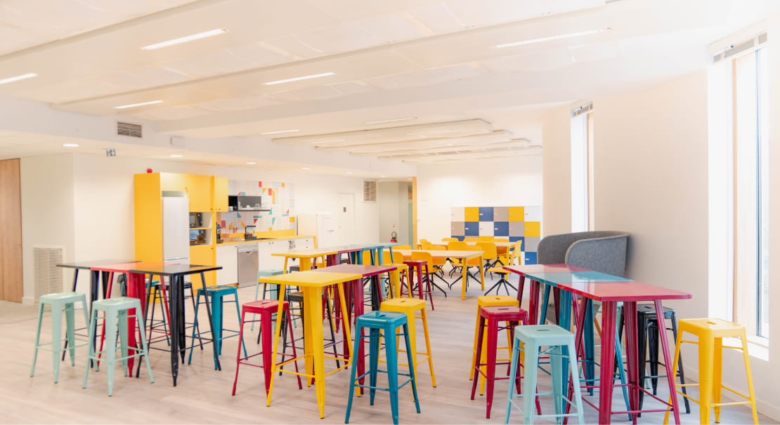 Espace détente coloré à Pantin – Hiptown Canal de l’Ourcq, cuisine équipée et mobilier design pour des pauses conviviales dans un environnement lumineux et moderne.