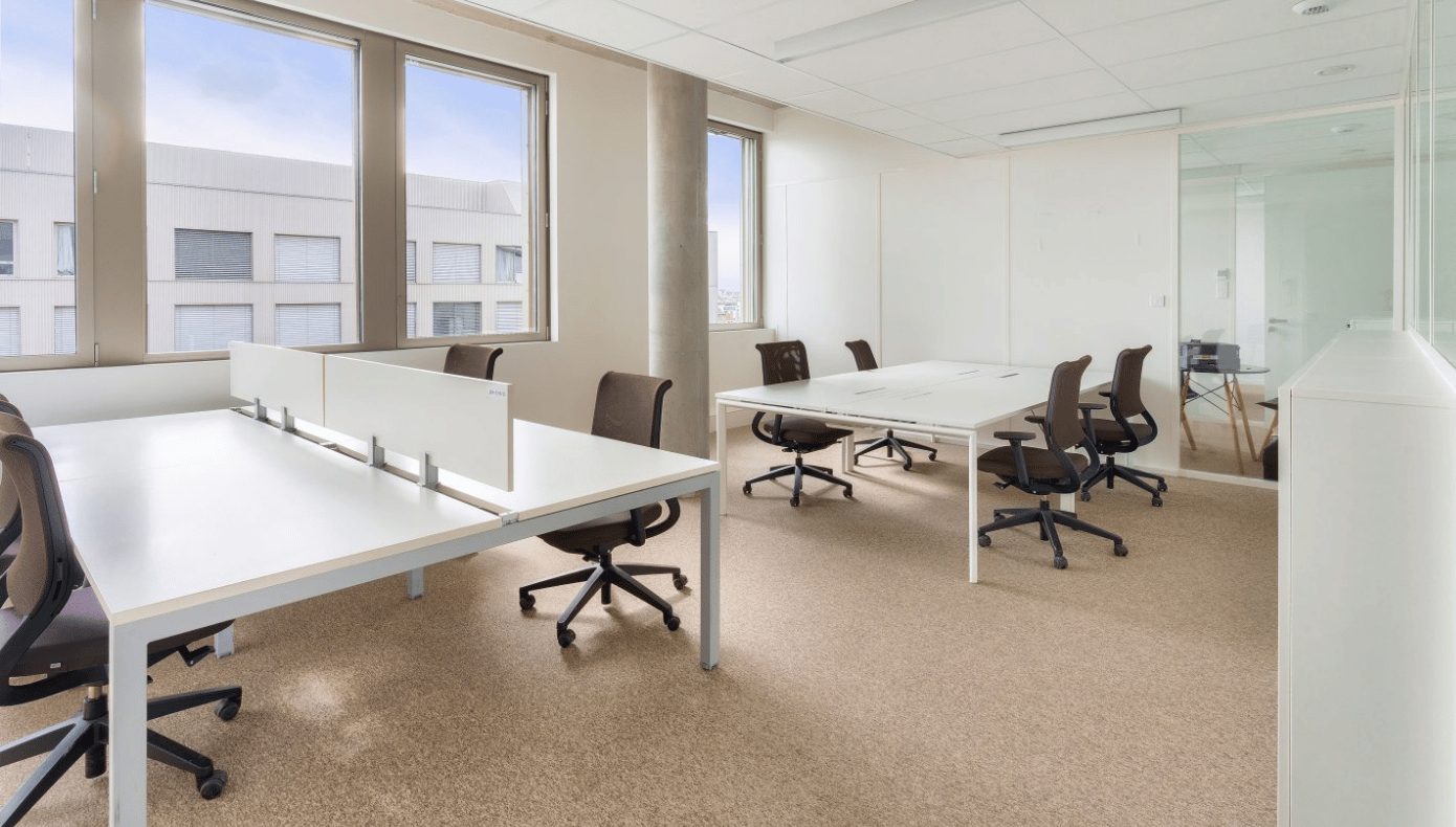 Bureau privatif lumineux avec plusieurs postes de travail, chaises de bureau et grandes fenêtres à Bordeaux.