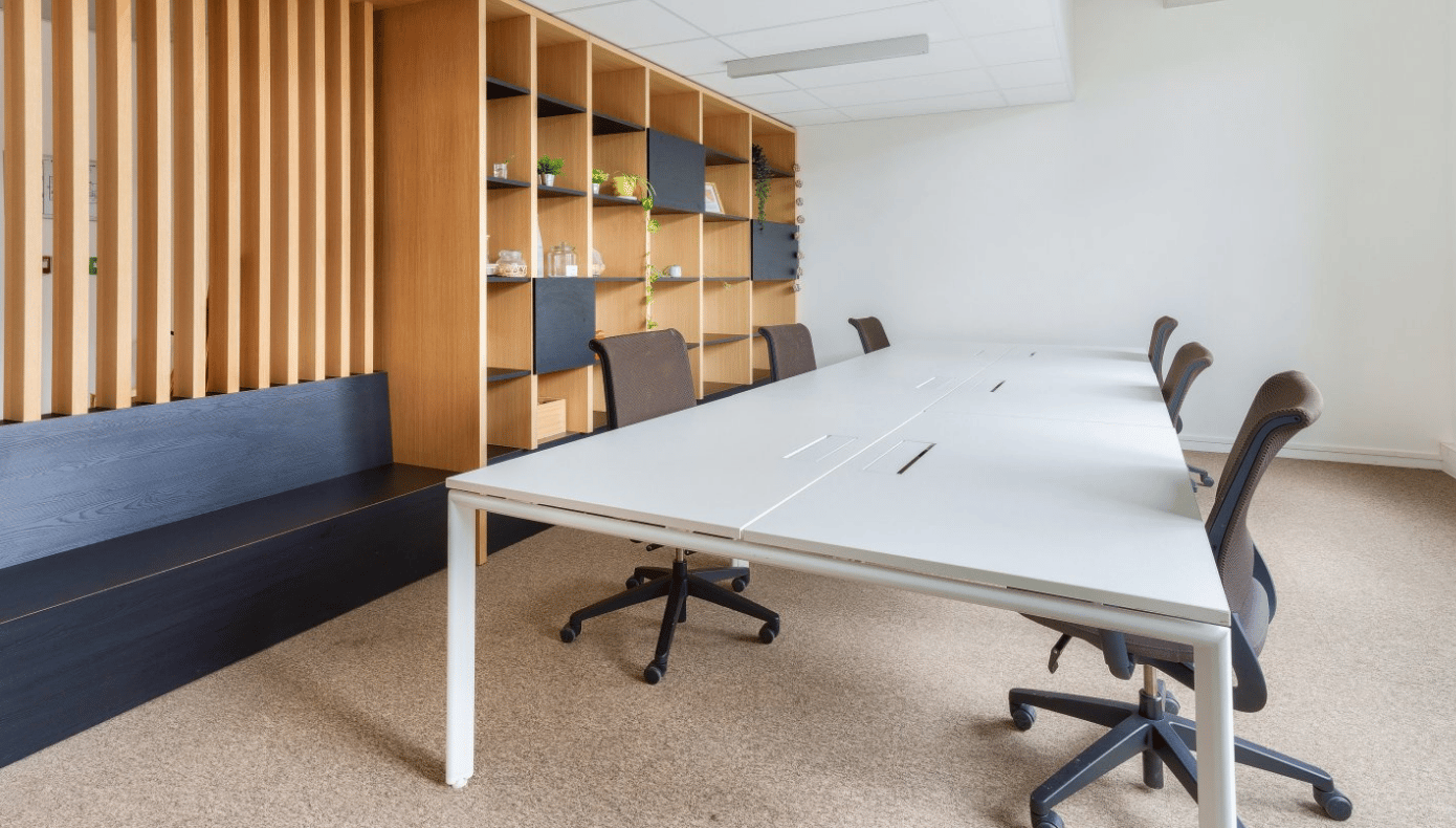 Bureau privatif à Bordeaux avec grande table partagée, sièges de travail, banquette et rangements en bois.