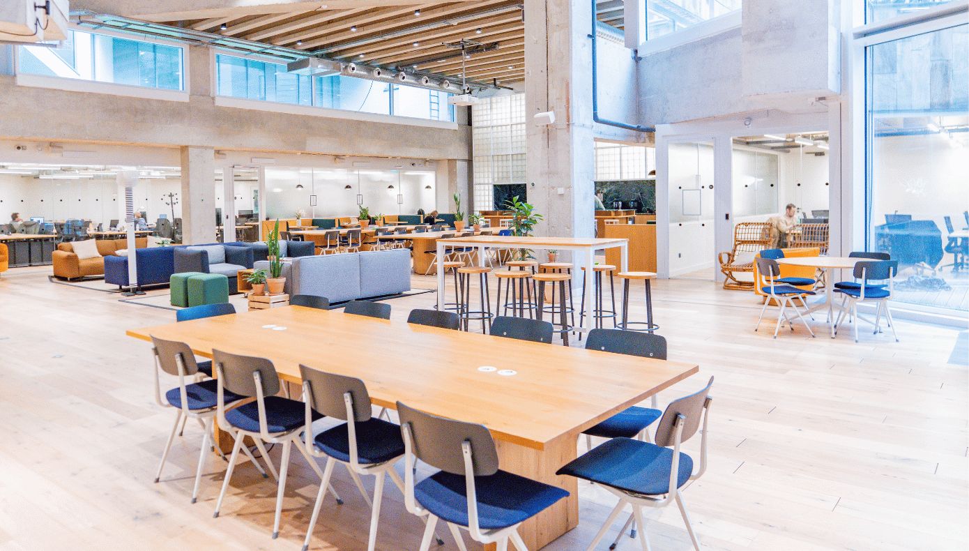 Espace de coworking à Porte Maillot Espace de coworking Hiptown Porte Maillot avec grande table partagée, salons, plantes et larges baies vitrées.