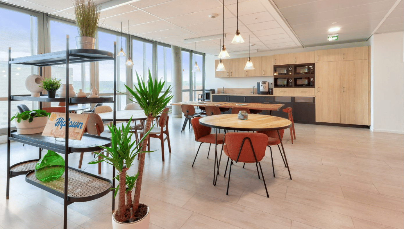 Espace commun Hiptown à Bordeaux avec cuisine partagée, tables, assises et plantes près des baies vitrées.