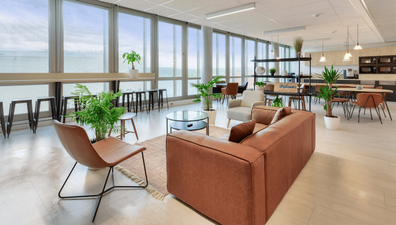 Espace lounge Hiptown à Bordeaux avec canapé, fauteuils, tables basses, plantes et grandes baies vitrées.