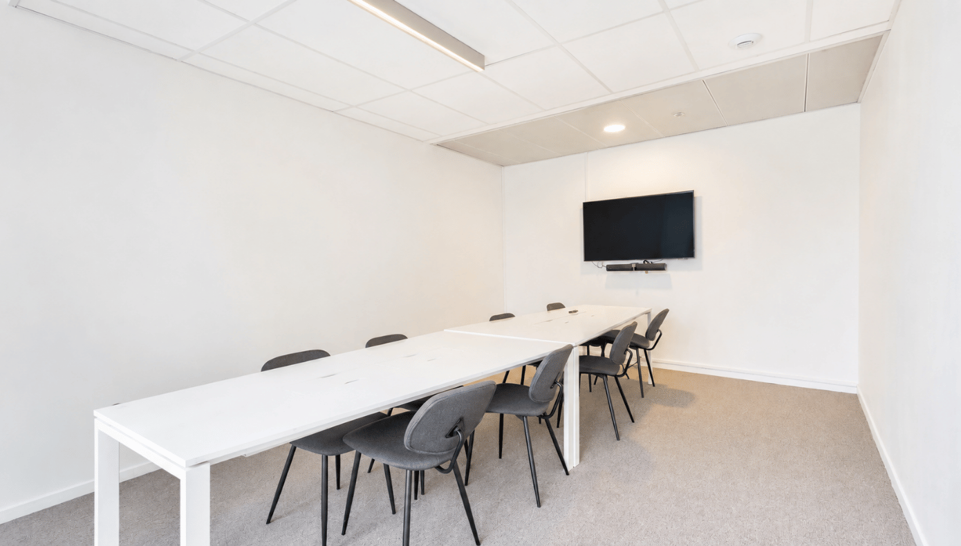 Salle de réunion Emergence à Bordeaux avec longue table, chaises et écran mural pour les présentations.