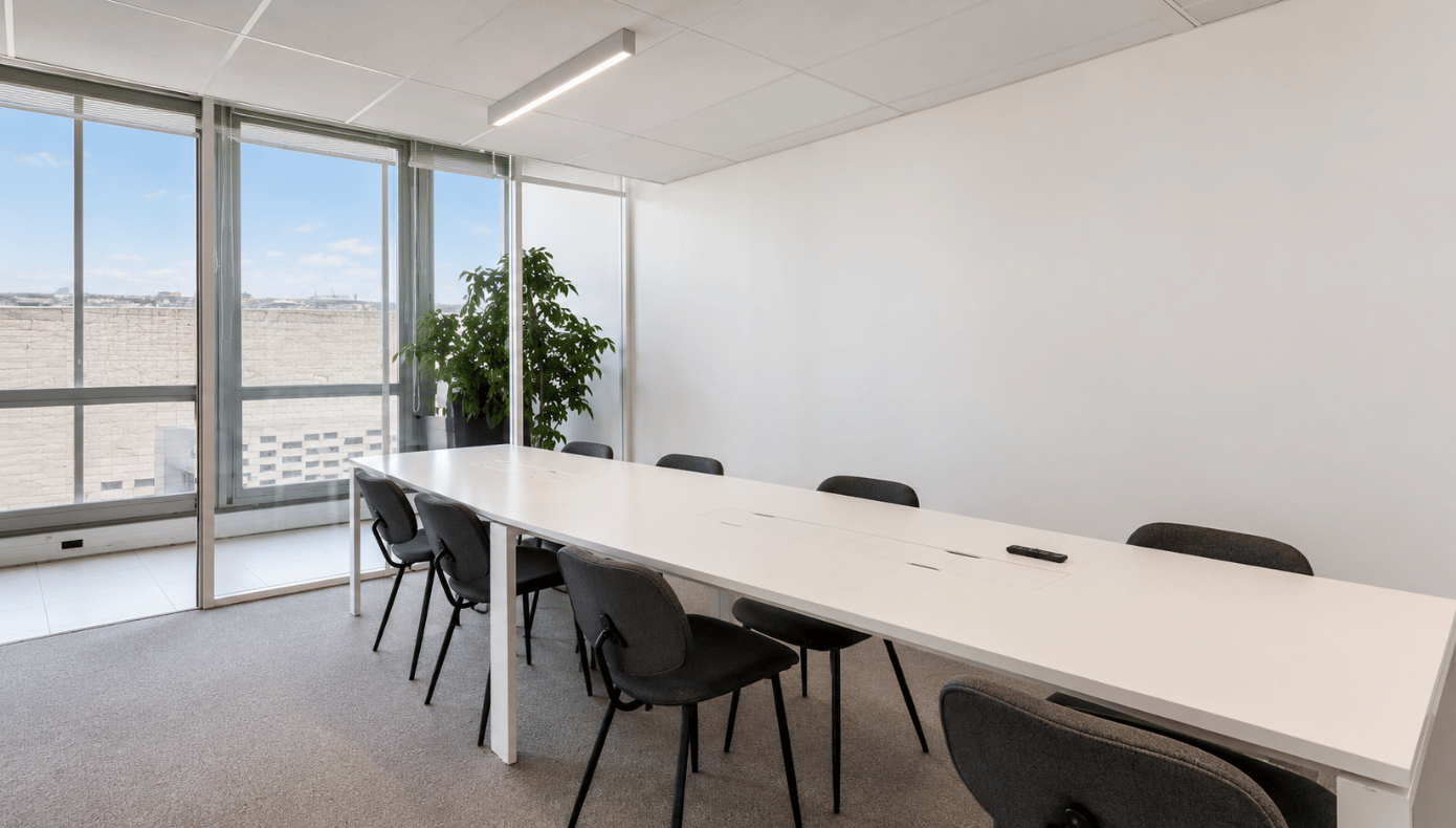 Salle de réunion Emergence à Bordeaux avec longue table, chaises, cloison vitrée et grandes fenêtres.