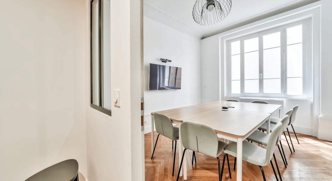 Salle de réunion à Hiptown Lyon Brotteaux avec table en bois, chaises ergonomiques et écran pour présentations