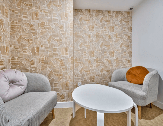 Espace de coworking à Hiptown Lyon Brotteaux avec fauteuils modernes, table basse blanche et décoration murale géométrique beige et blanche