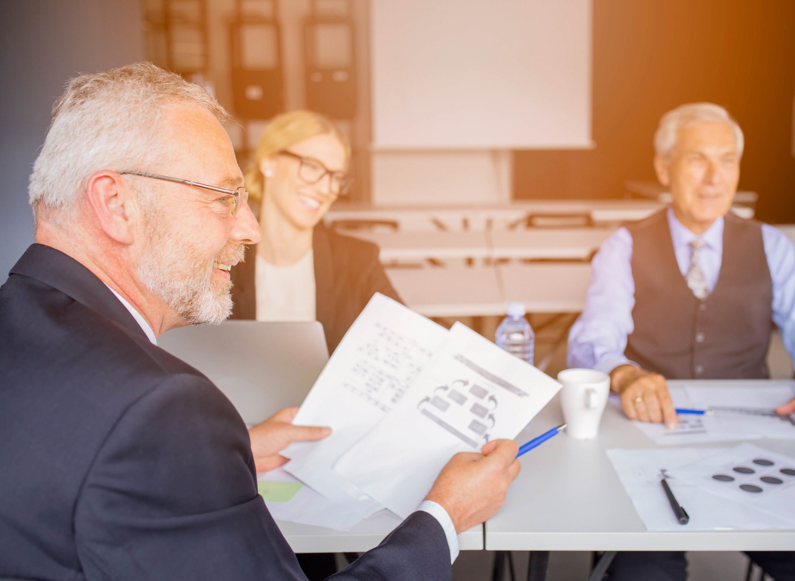 Réunion professionnelle avec trois collègues discutant de documents, symbolisant la signature de contrat