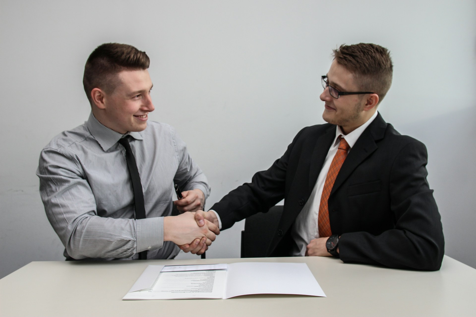 Deux hommes en tenue professionnelle se serrant la main après la signature d'un contrat de location de bureau