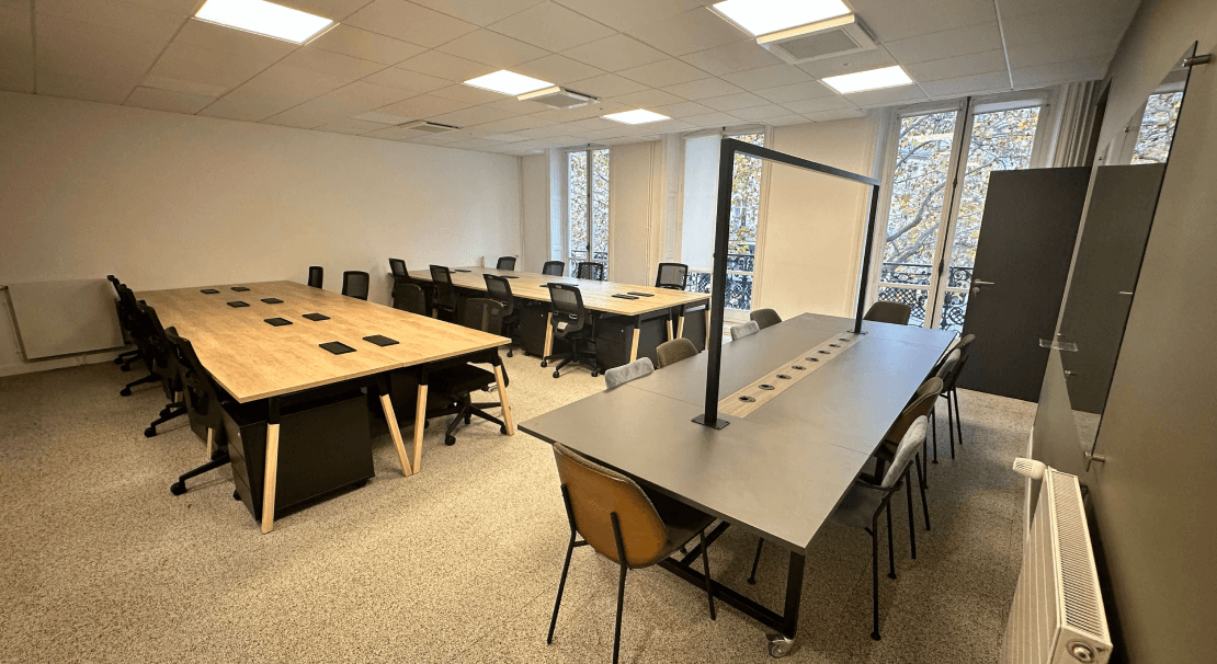 Espaces de travail modernes à Paris Madeleine avec de grandes tables en bois, chaises ergonomiques et lumière naturelle grâce à de grandes fenêtres