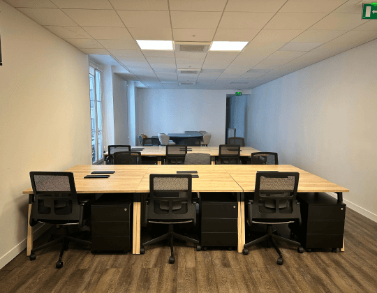 Espace de coworking à Paris Madeleine avec des bureaux partagés en bois, chaises ergonomiques et lumière naturelle pour un environnement de travail optimal