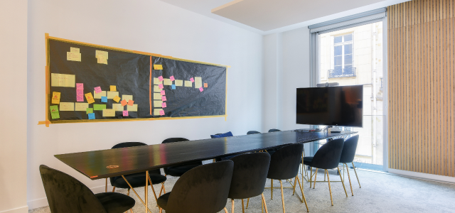Salle de réunion moderne à Paris, rue du 4 Septembre, équipée d'un tableau collaboratif, d'une télévision et de chaises confortables pour des sessions productives