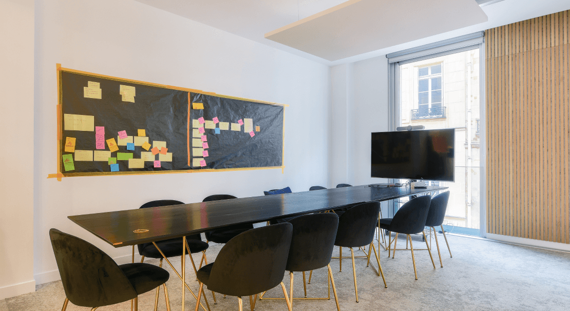 Salle de réunion moderne à Paris, rue du 4 Septembre, équipée d'un tableau collaboratif, d'une télévision et de chaises confortables pour des sessions productives