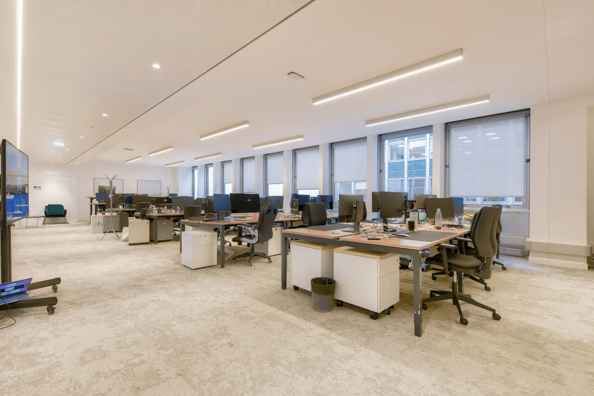 Open space lumineux et moderne à Paris, rue du 4 Septembre, avec des postes de travail équipés, fauteuils ergonomiques et grandes fenêtres pour une ambiance professionnelle