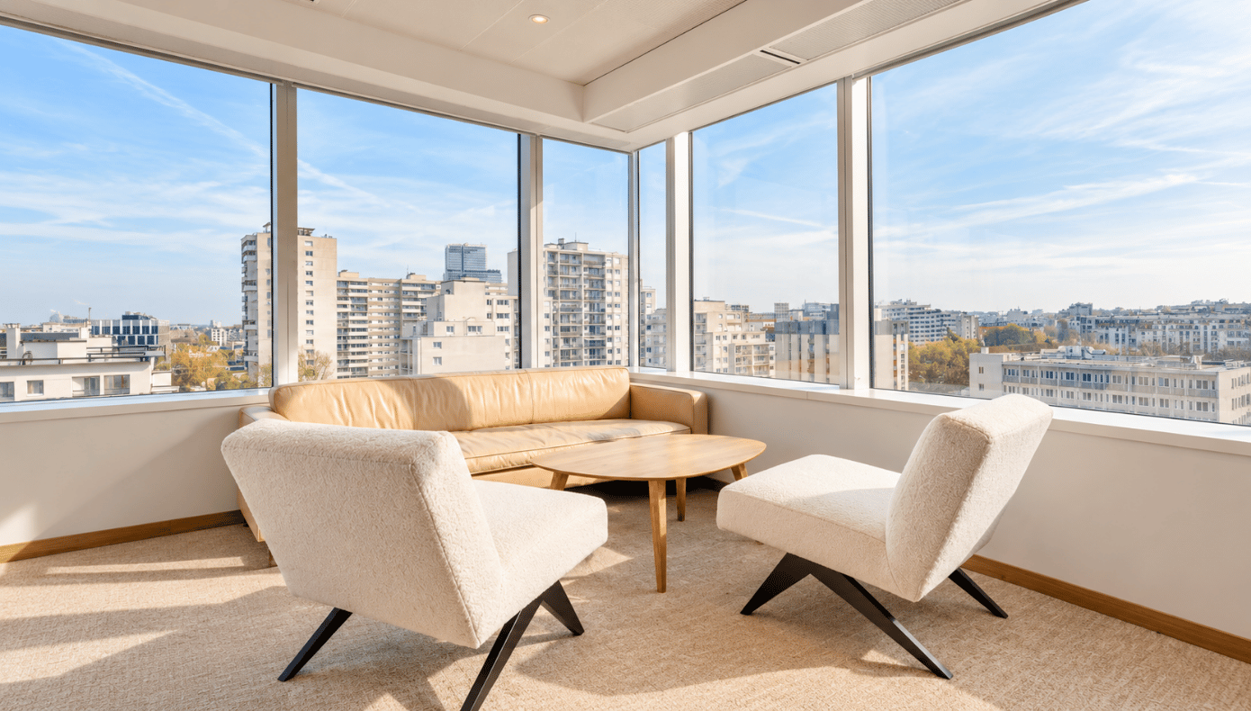Coin détente avec canapé, fauteuils et table basse près de grandes baies vitrées à Levallois.