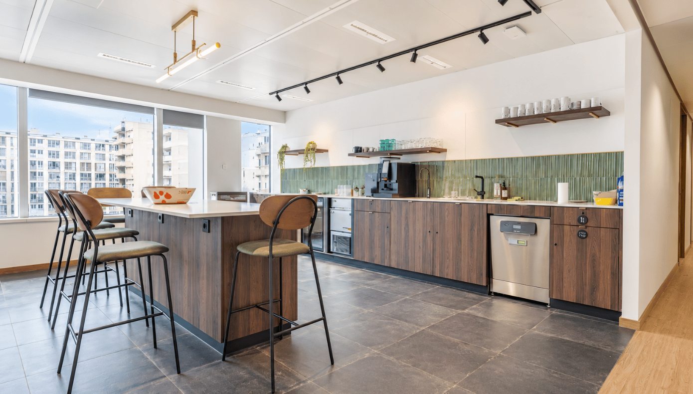 Cuisine partagée à Levallois avec îlot central, tabourets hauts, rangements et grandes fenêtres.