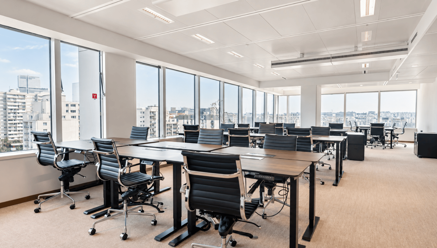 Plateau de bureaux flexibles à Levallois avec postes de travail, fauteuils noirs et grandes baies vitrées.