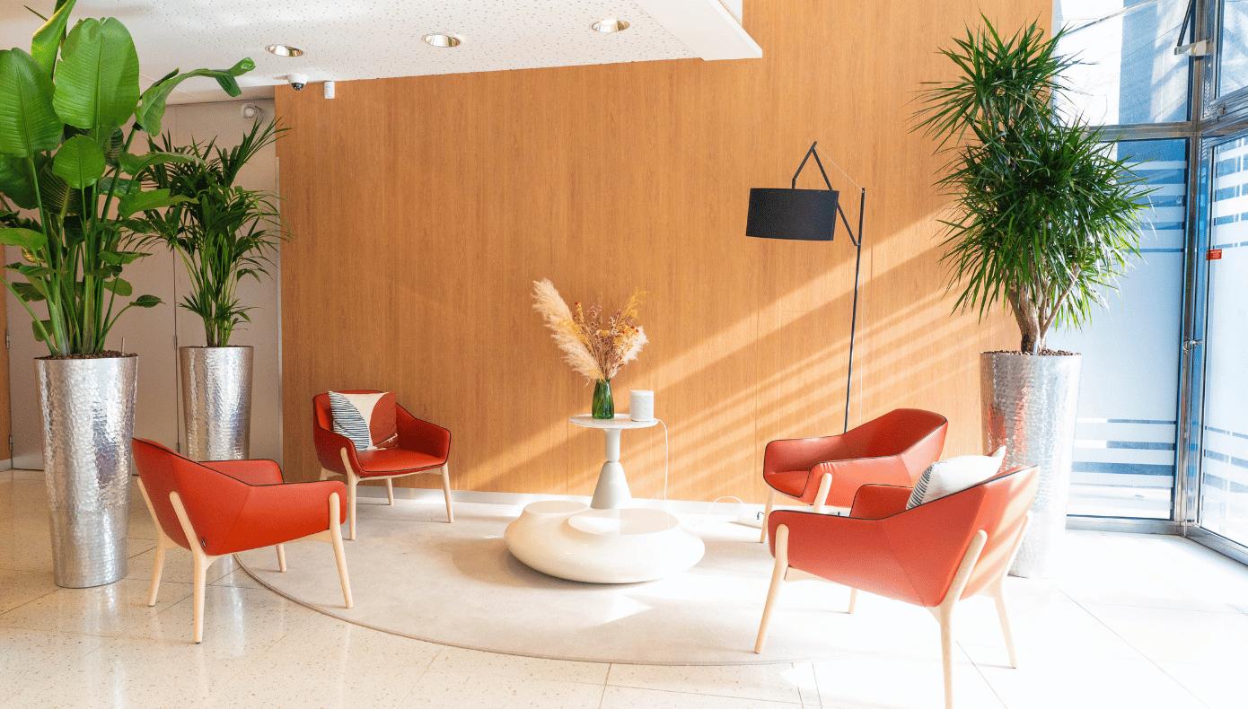 Espace lounge végétalisé à Boulogne Espace lounge de Hiptown Boulogne avec fauteuils rouges, tables basses et grandes plantes près des baies vitrées.