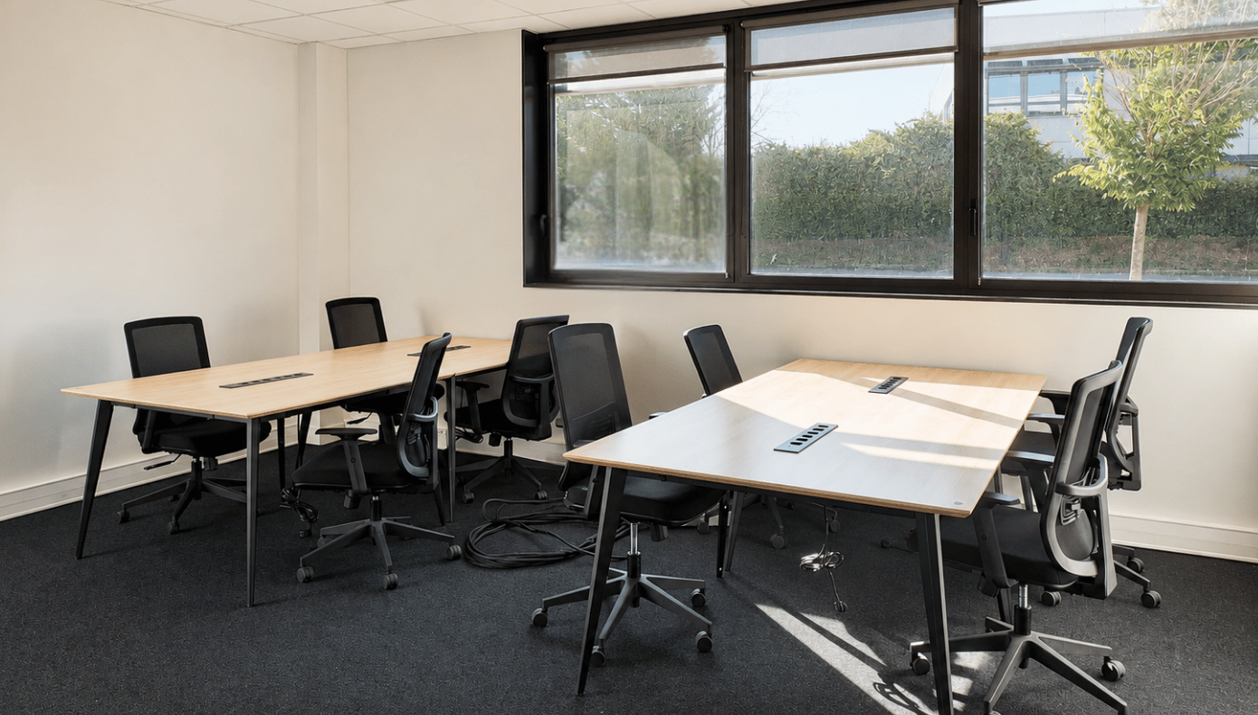 Espace de travail avec grandes tables équipées, baies vitrées et vue directe sur les espaces verts extérieurs.
