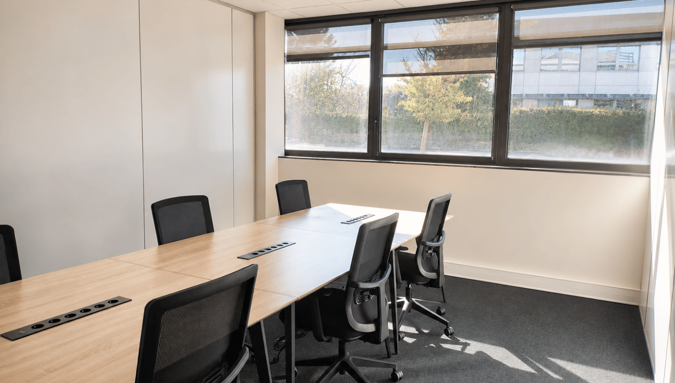 Espace de travail avec grandes tables équipées, baies vitrées et vue directe sur les espaces verts extérieurs.
