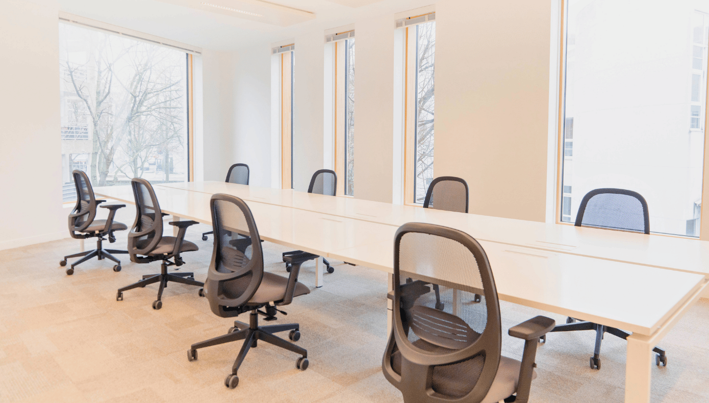 Espace de travail partagé à Pantin avec longues tables, fauteuils de bureau et grandes fenêtres.