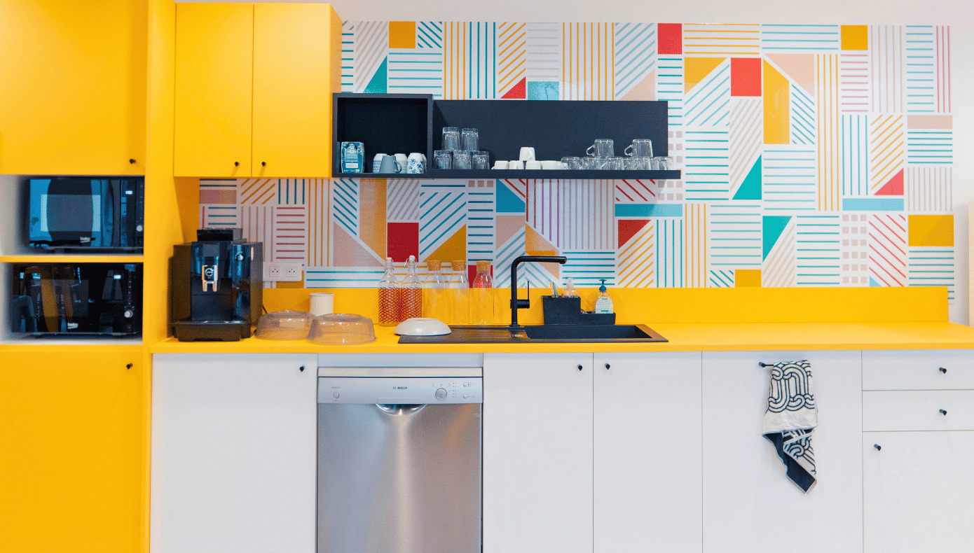 Kitchenette équipée à Pantin avec évier, lave-vaisselle, micro-ondes, machine à café et rangements jaunes.